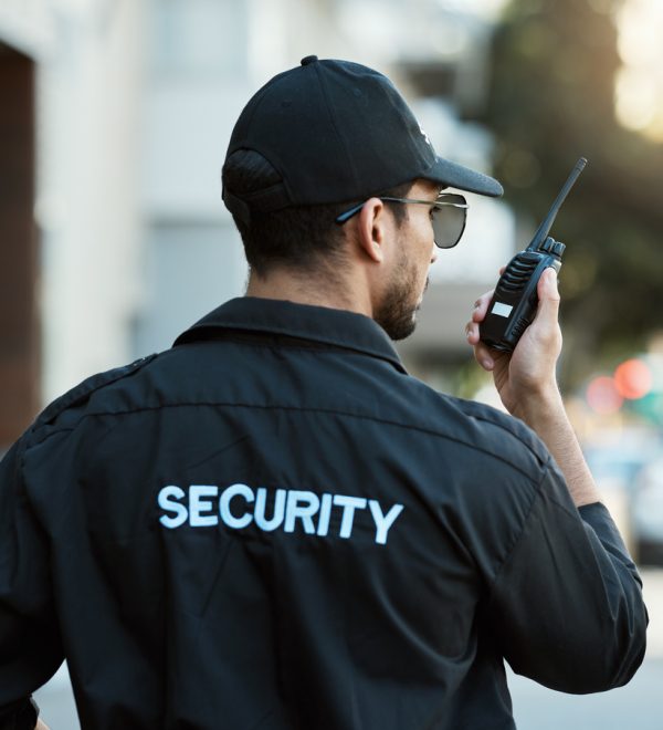 Radio, man and a security guard or safety officer outdoor on a city road for communication. Back of a person with a walkie talkie on urban street to report crime for investigation and surveillance